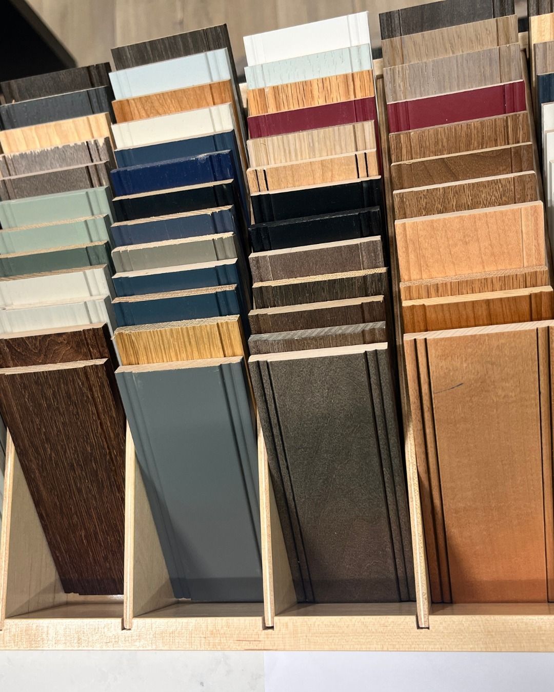 Display of various colored wooden frame samples in a wooden holder.