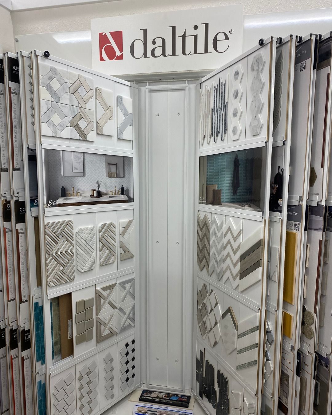 Daltile tile display showcasing various tile samples in a showroom setting. White and gray tiles dominate the display.