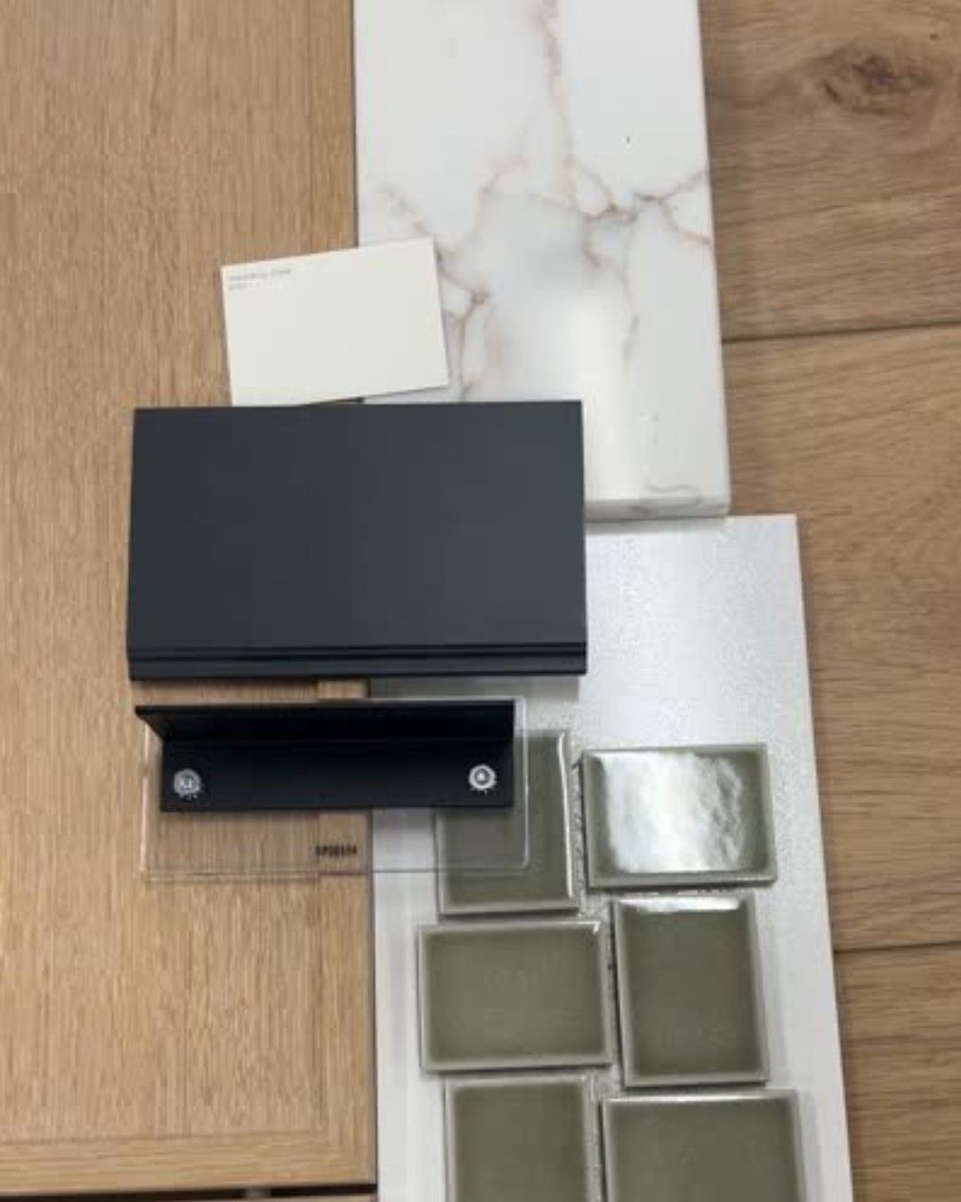 Wood, white, and gray material samples with black hardware, for interior design.