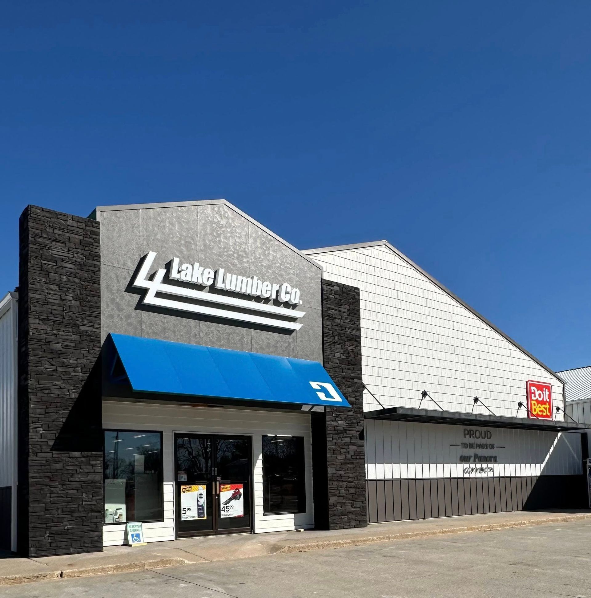 Lake Lumber Co. building with a blue awning and dark brick accents against a blue sky.