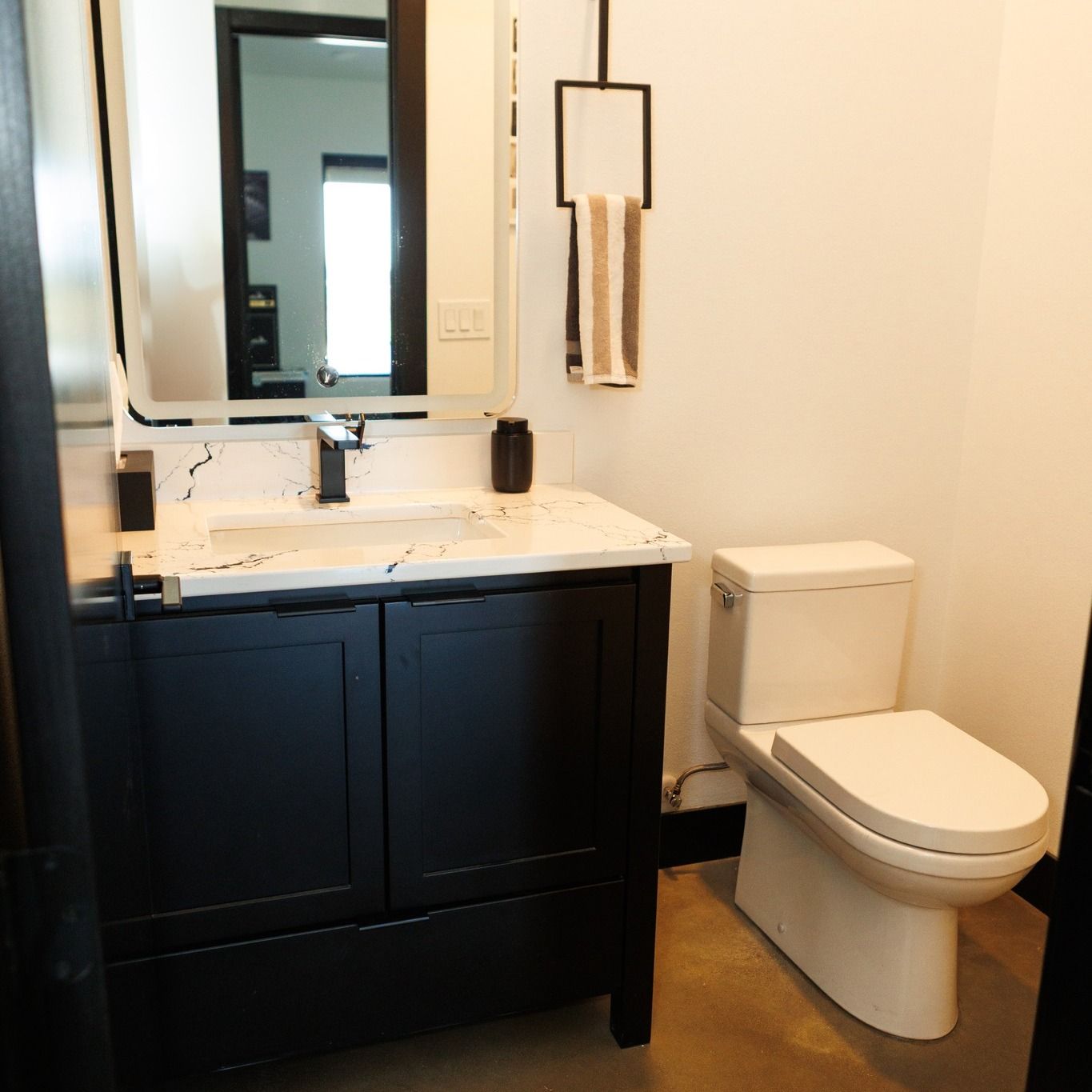 Bathroom with a black vanity, white toilet, and towel rack.