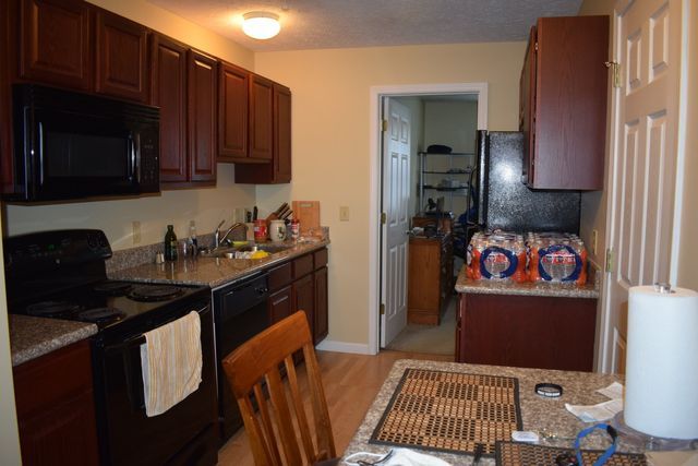 A kitchen with a table, chairs, stove, microwave, and refrigerator.