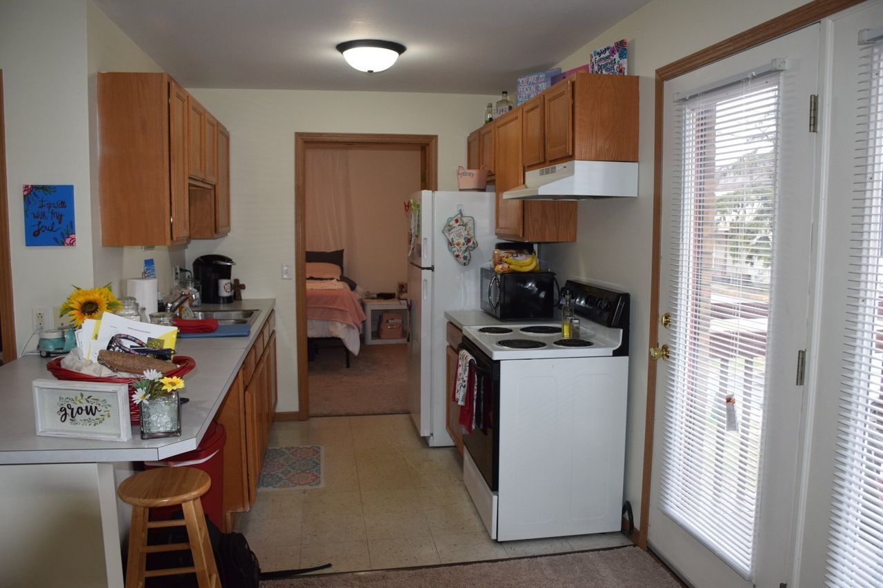 A kitchen with a stove, refrigerator, and stools.
