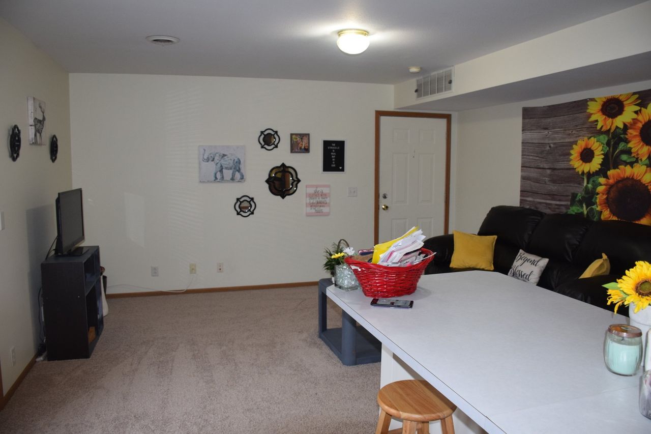 A living room with a couch, table, television and sunflowers on the wall.