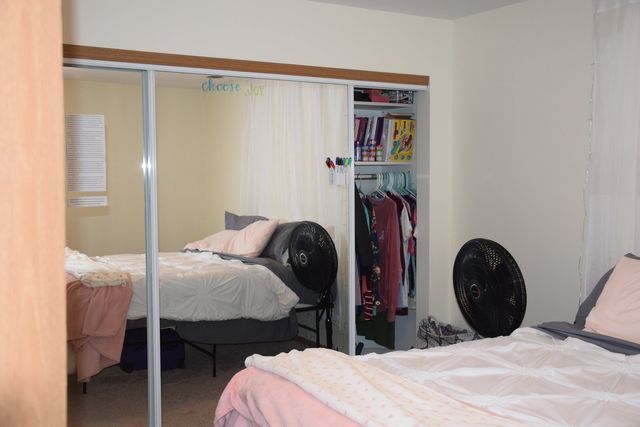 A bedroom with a bed and a closet with sliding glass doors.