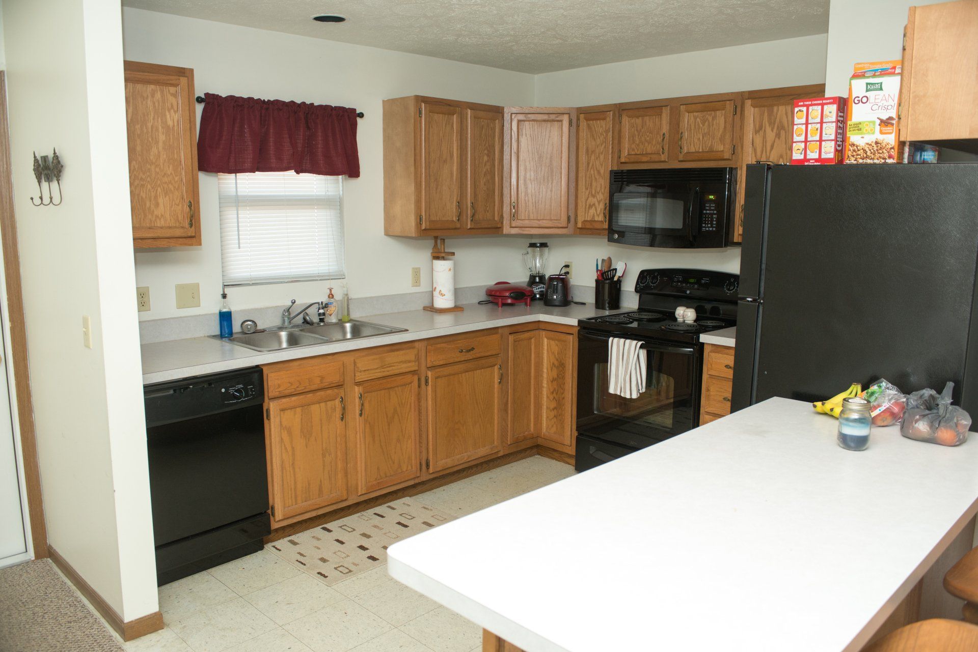 A kitchen with wooden cabinets and a black refrigerator.