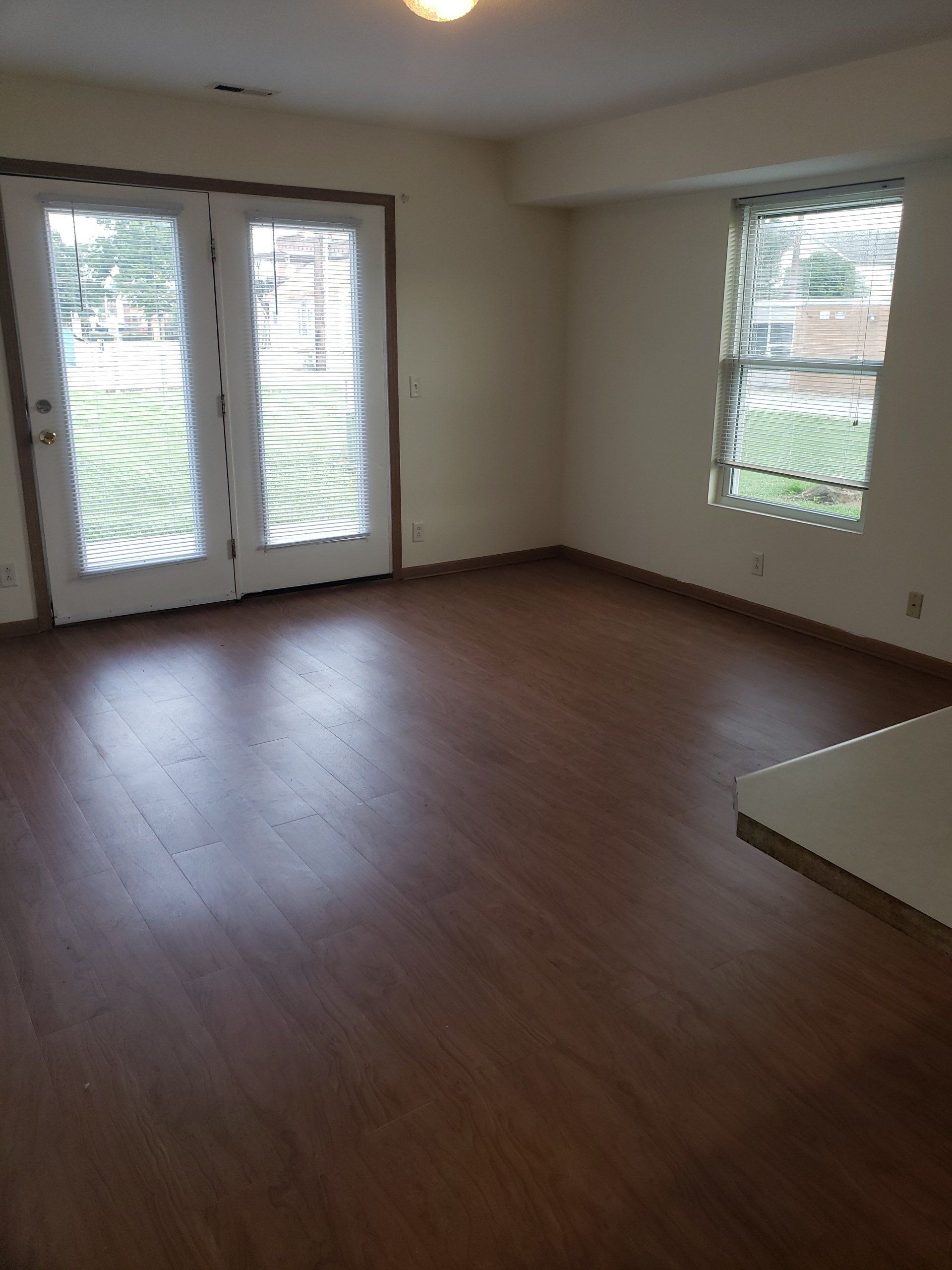 An empty living room with hardwood floors and sliding glass doors.
