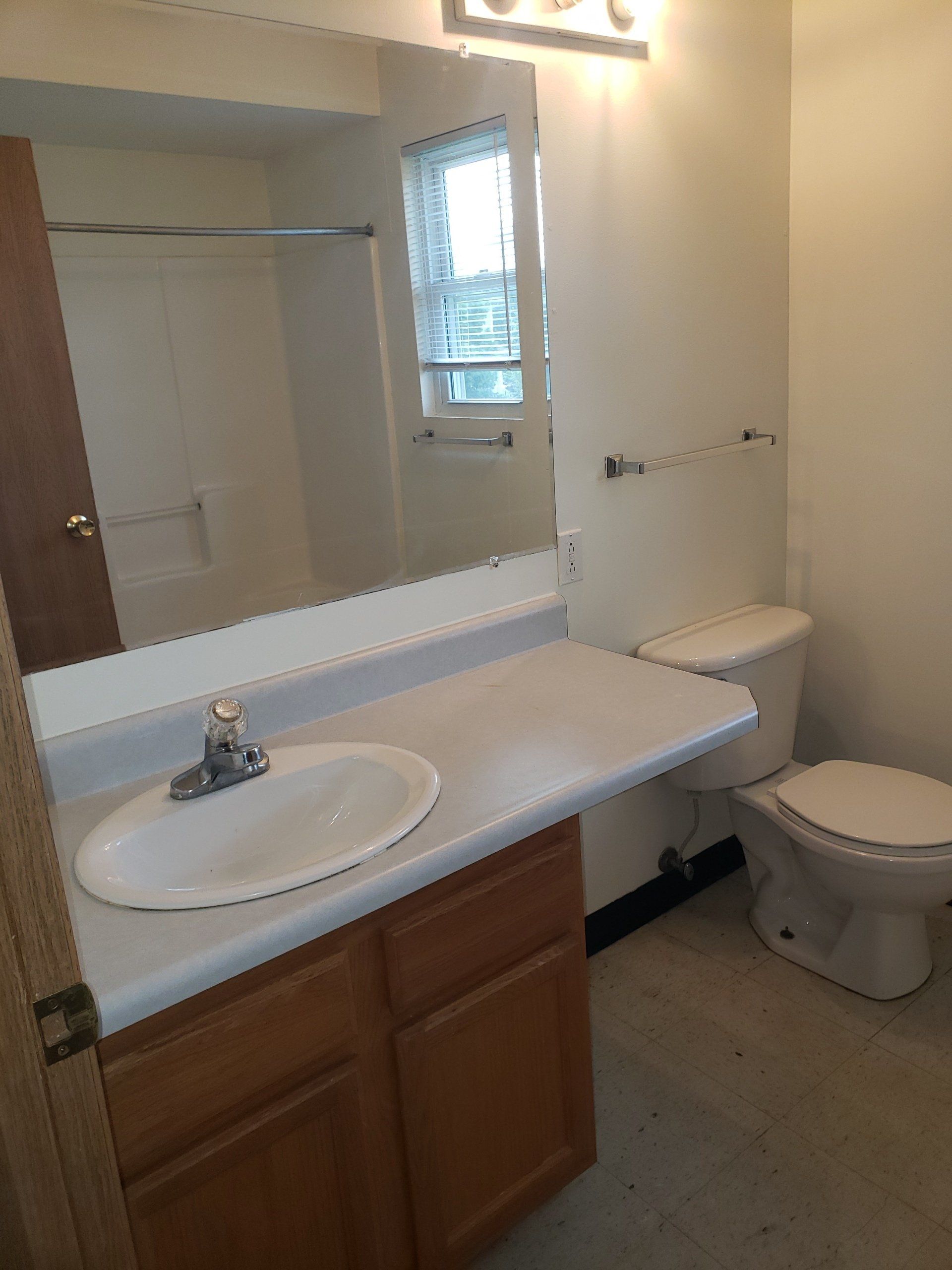 A bathroom with a sink, toilet, and mirror.