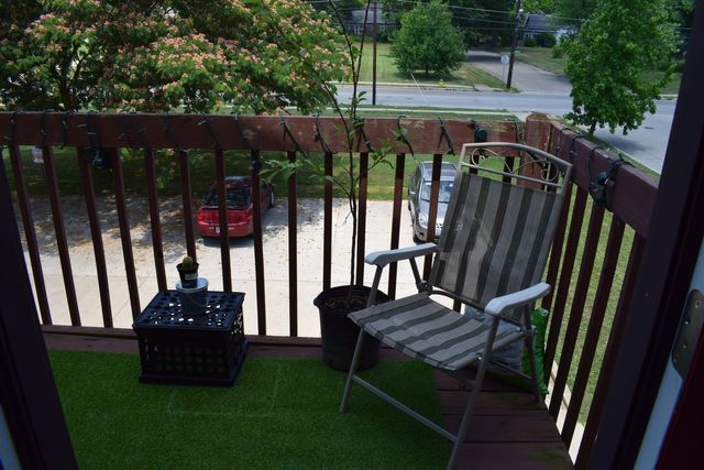 A balcony with a chair and potted plants on it.