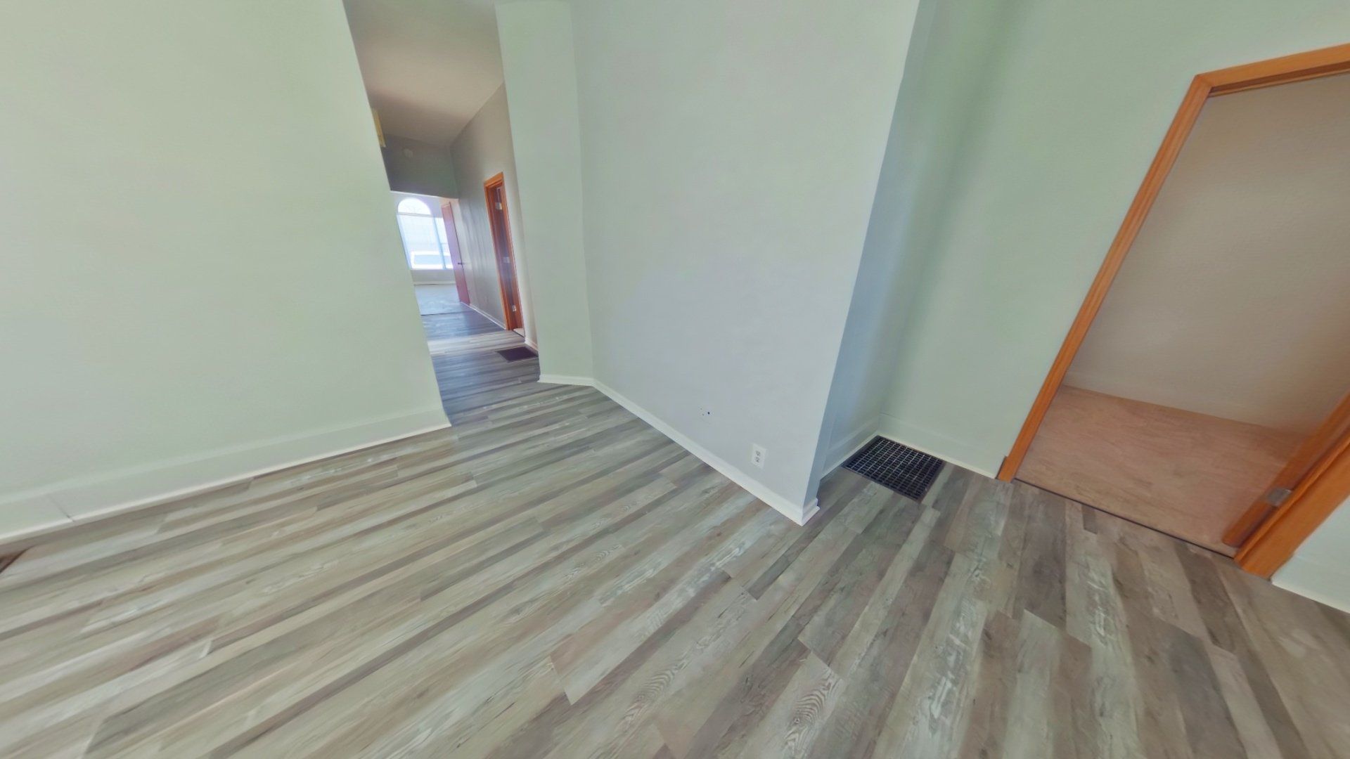 An empty room with hardwood floors and white walls.