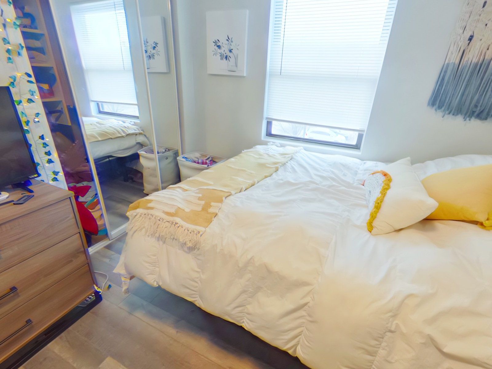 A bedroom with a bed, dresser, television and mirror.