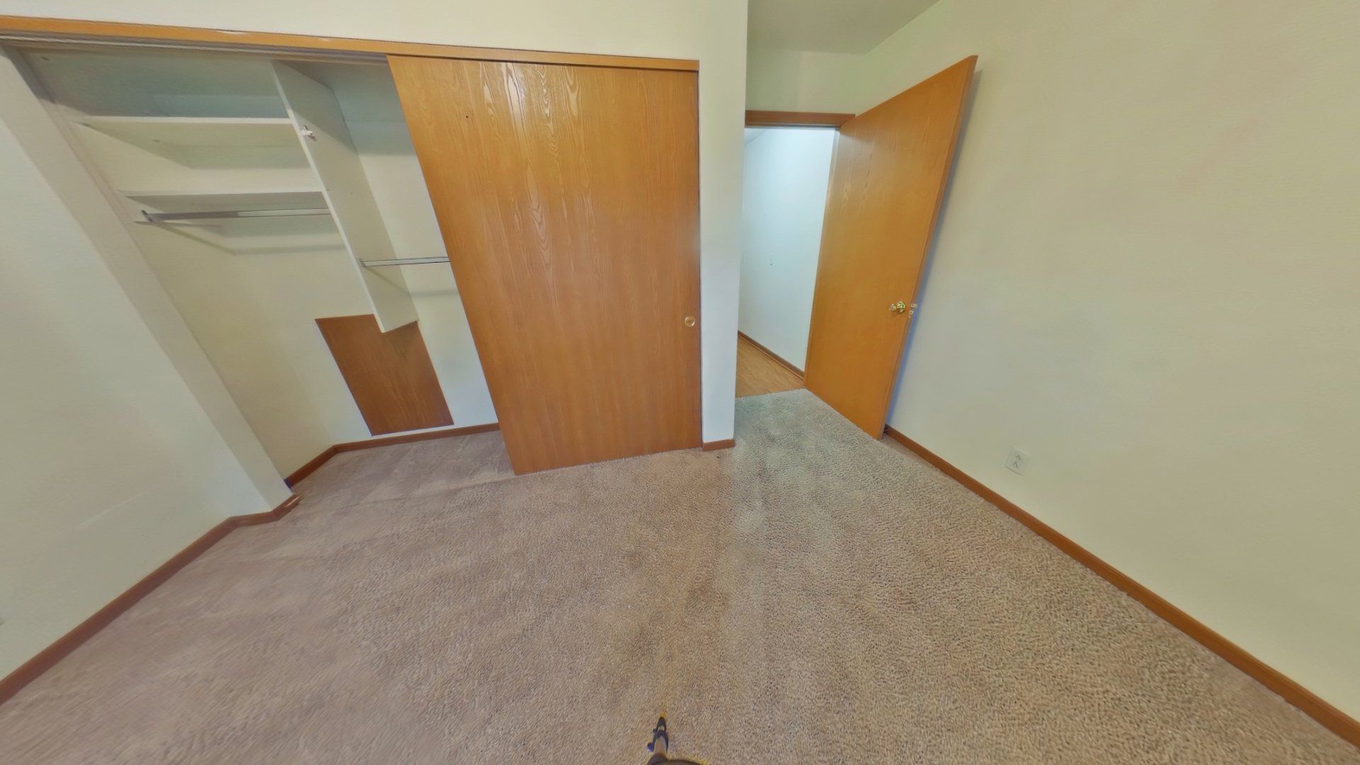 An empty bedroom with a closet and sliding doors.