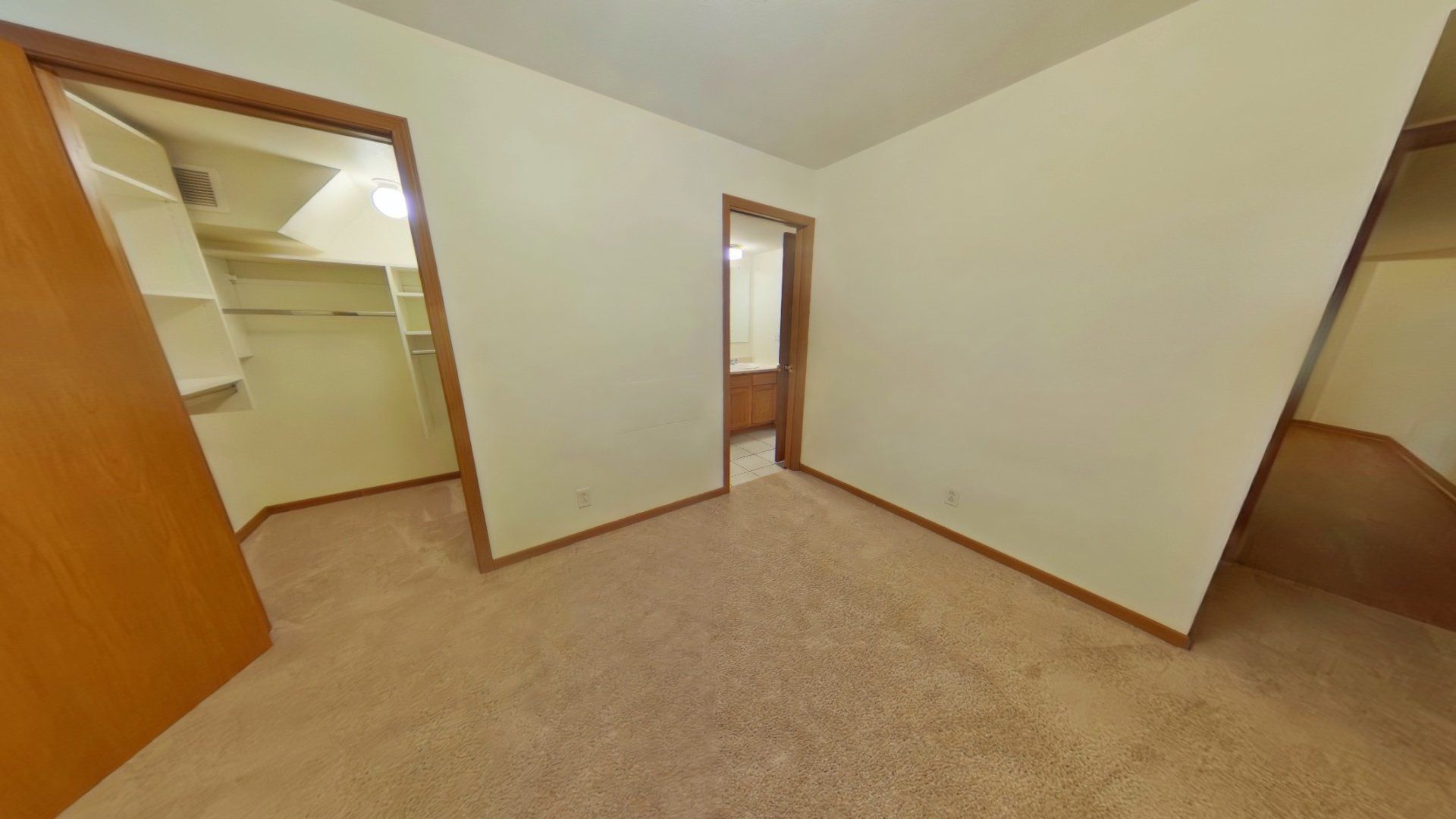 A bedroom with a walk in closet and a bathroom.