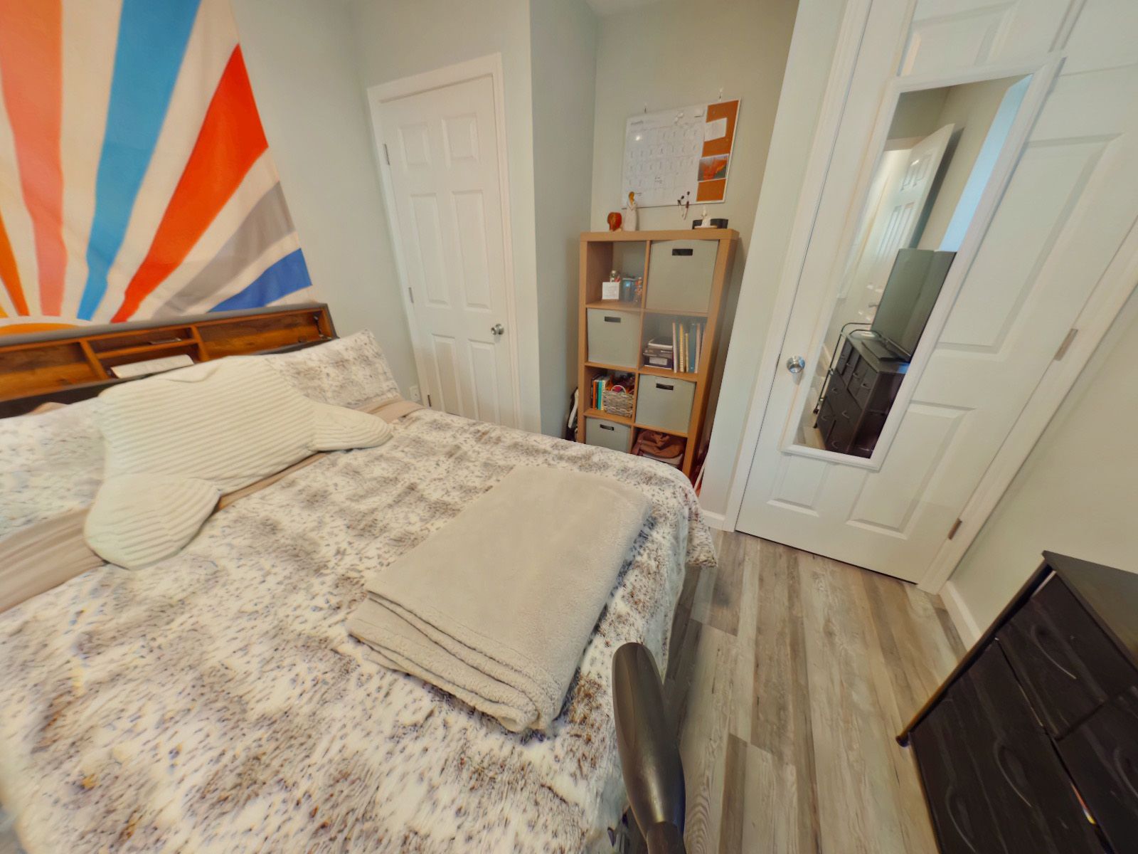 A bedroom with a bed a dresser and a mirror.