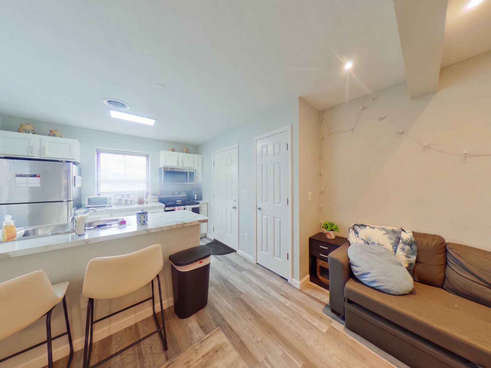 A living room with a couch and a kitchen in the background.