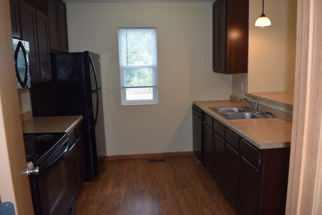 A kitchen with a refrigerator, sink, stove, and microwave.