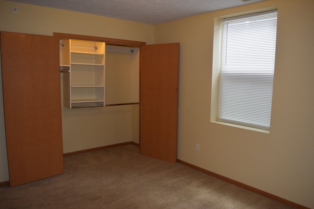 An empty bedroom with a closet and a window.