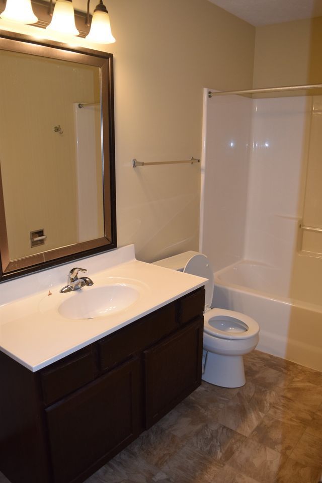 A bathroom with a sink, toilet, tub, and mirror.