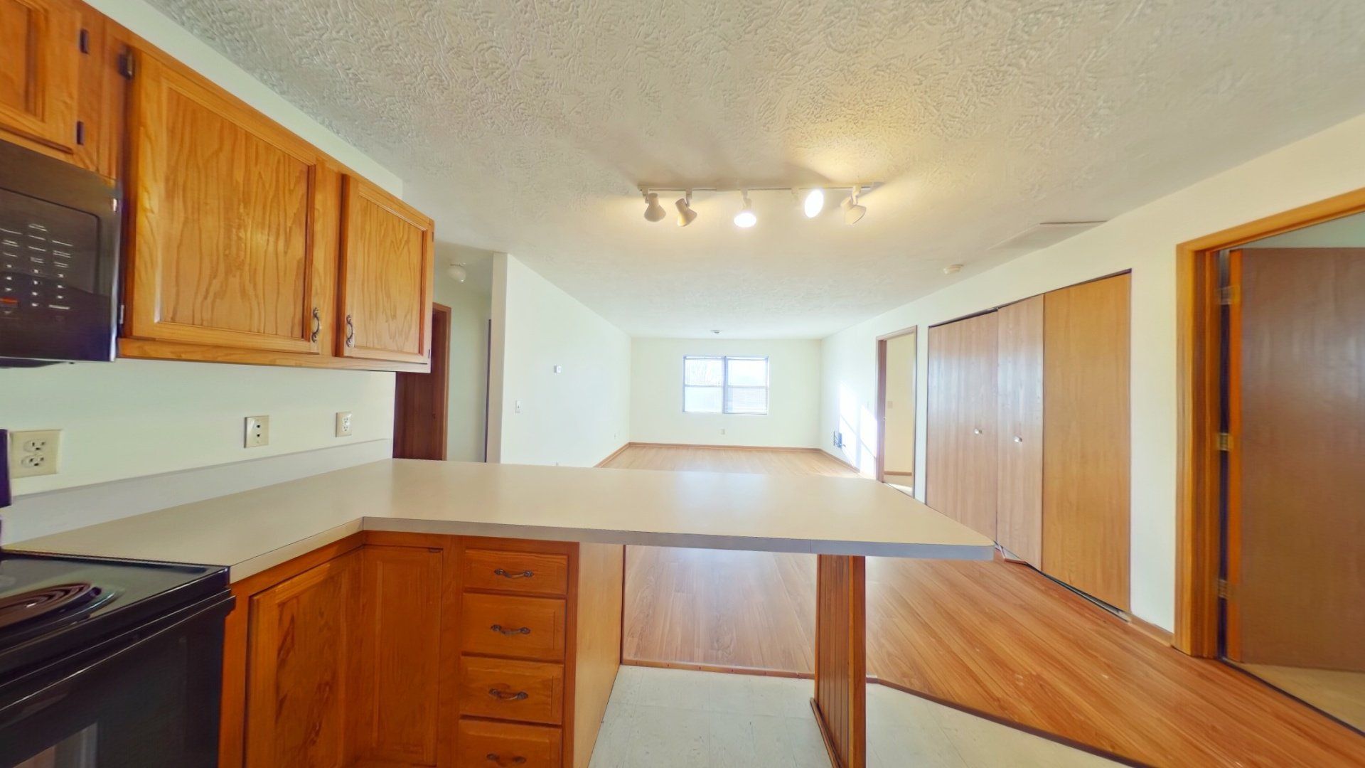 An empty kitchen with wooden cabinets and hardwood floors.