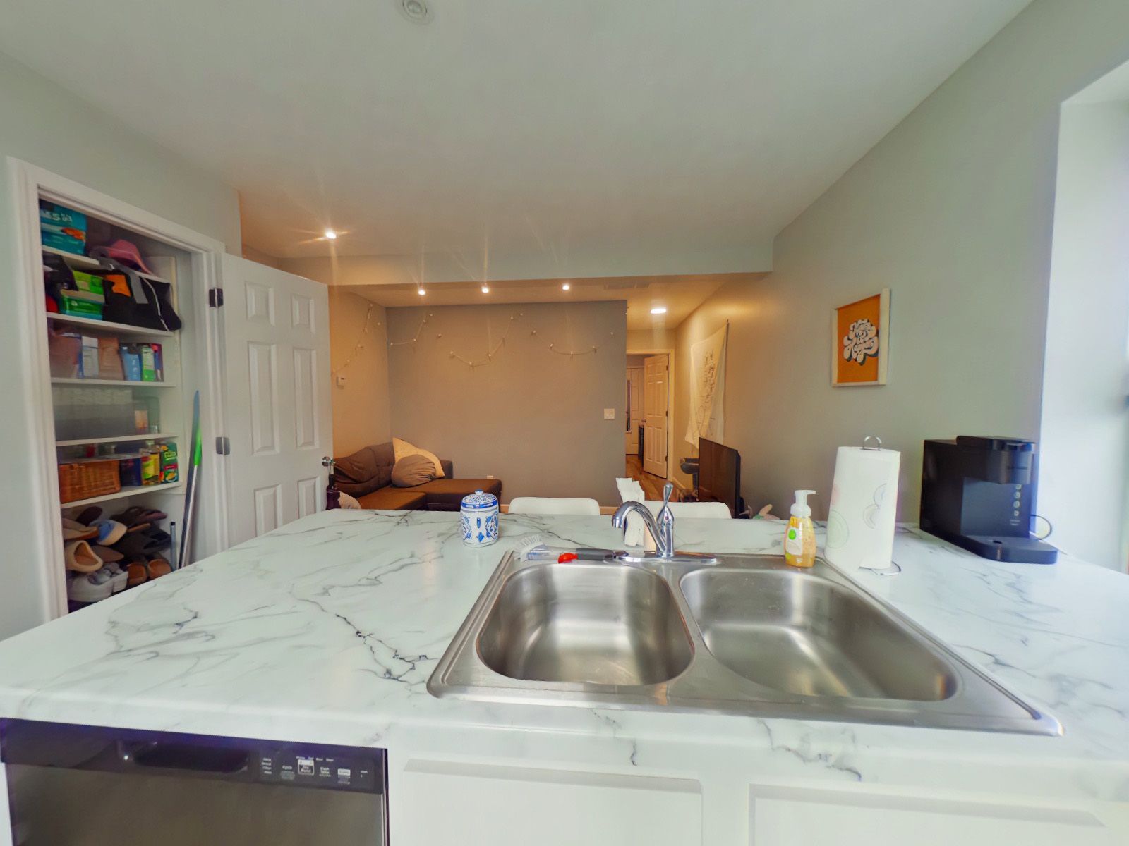 A kitchen with a sink, dishwasher, and marble counter top.