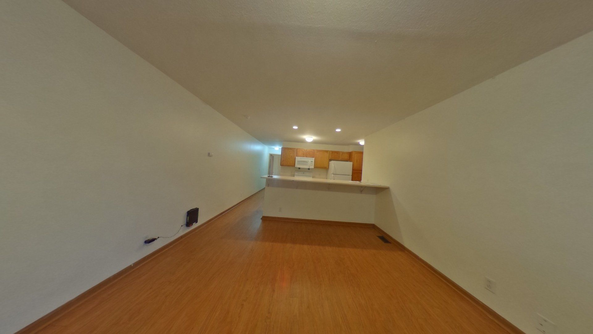 An empty living room with hardwood floors and white walls.