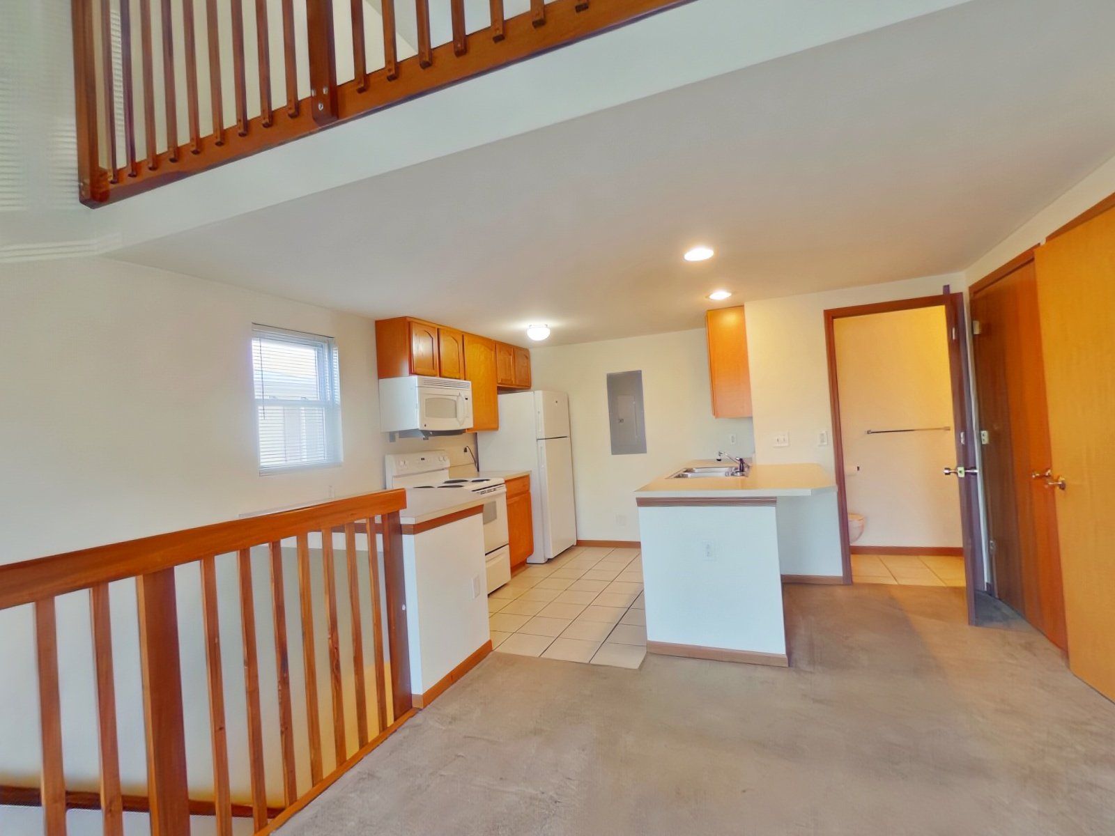 An empty kitchen with a staircase leading up to it.
