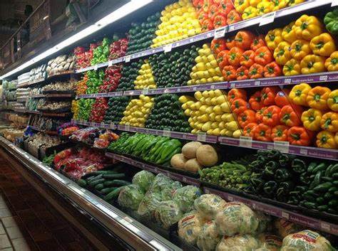 A grocery store aisle filled with lots of fruits and vegetables.