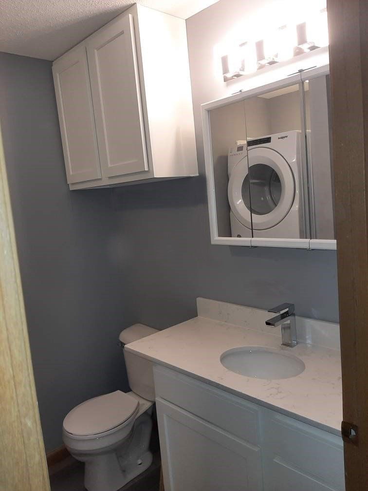 A bathroom with a toilet, sink, and washer and dryer.