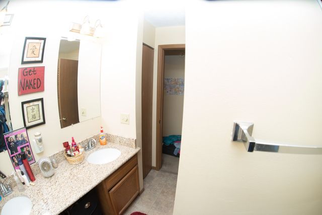 A bathroom with two sinks, a mirror, and a towel rack.