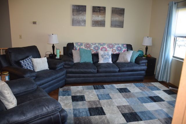 A living room with a couch, chairs, and a rug.