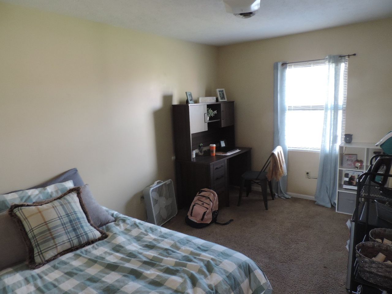 A bedroom with a bed a desk and a window.