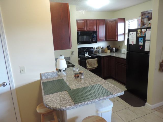 A kitchen with granite counter tops and a black refrigerator.