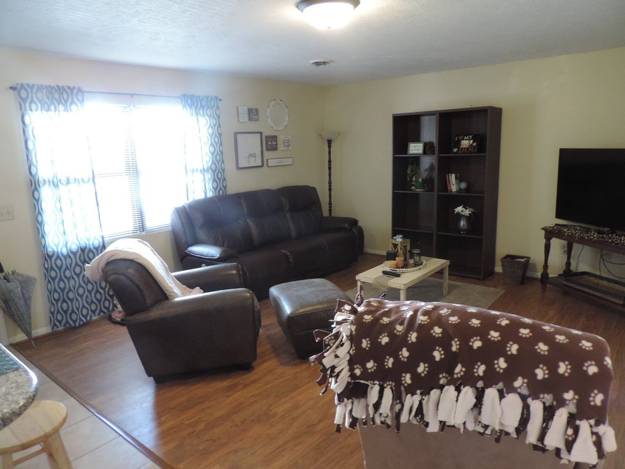 A living room with a couch and chairs and a television.