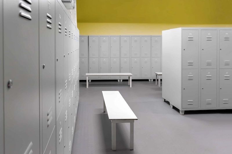 A locker room with lots of lockers and a bench.