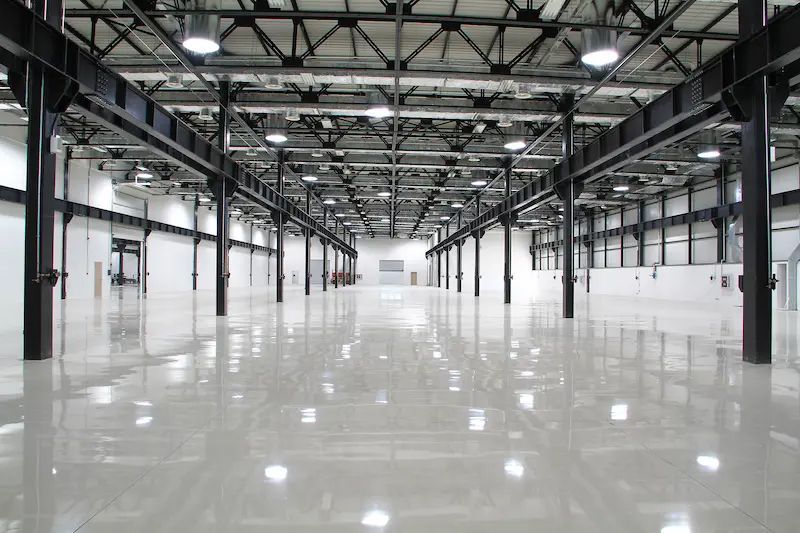 A large empty warehouse with a shiny floor and lots of lights.