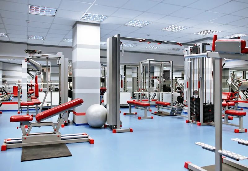 A gym filled with lots of exercise equipment and a treadmill.