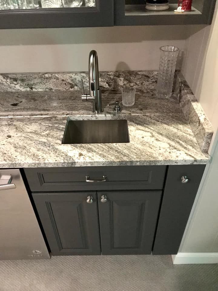Gray kitchen sink with granite countertop and dark gray cabinets. Stainless steel faucet and dishwasher.