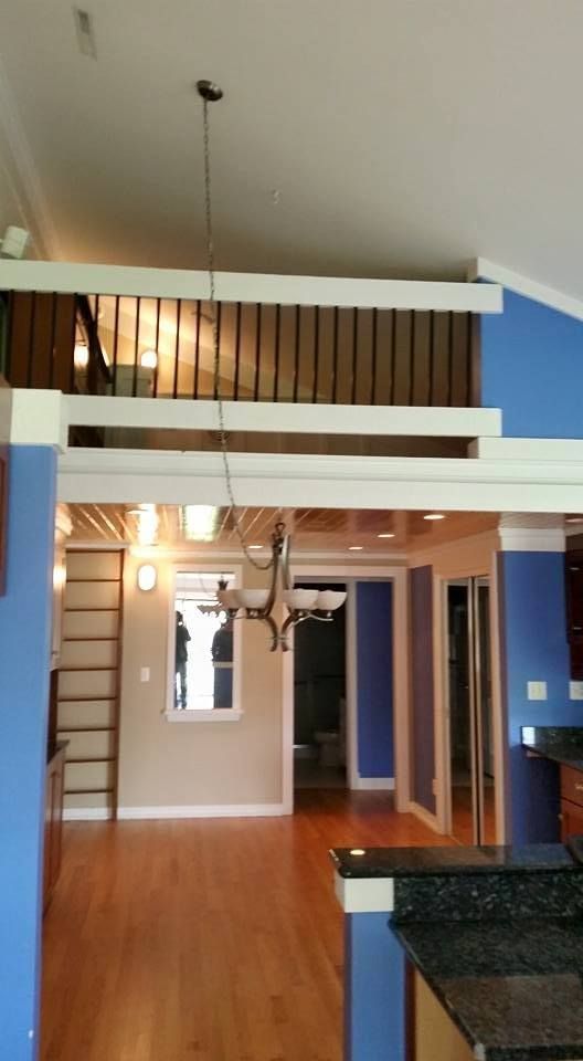 Interior view of a living space with loft, hardwood floors, and blue walls.