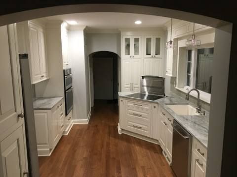 White kitchen with wooden floors and gray countertops.