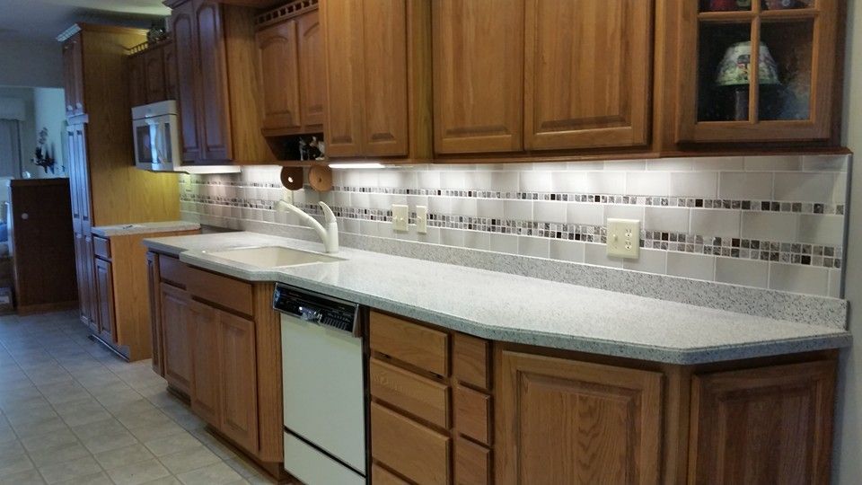 Kitchen with light wood cabinets, white countertops, and tiled backsplash.