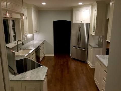 Bright kitchen with white cabinets, stainless steel refrigerator, and dark hardwood floors.