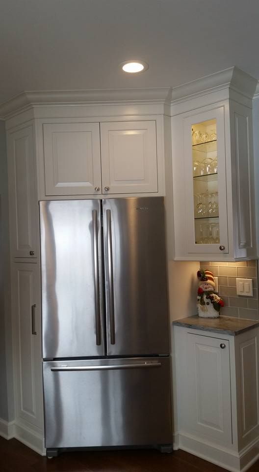 White kitchen cabinets with a stainless steel refrigerator.