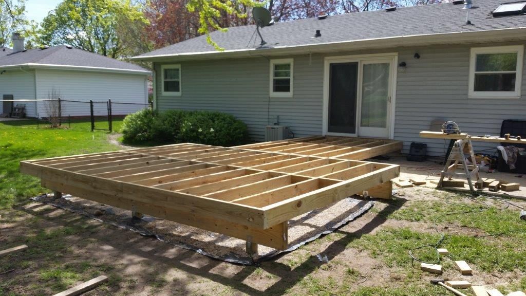 Wooden deck under construction in a backyard, sunny day.