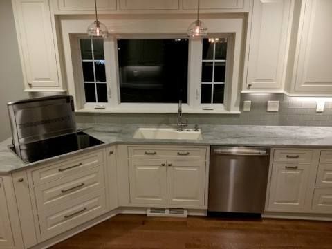 Cream-colored kitchen with white cabinetry, stainless steel appliances, and a window above the sink.