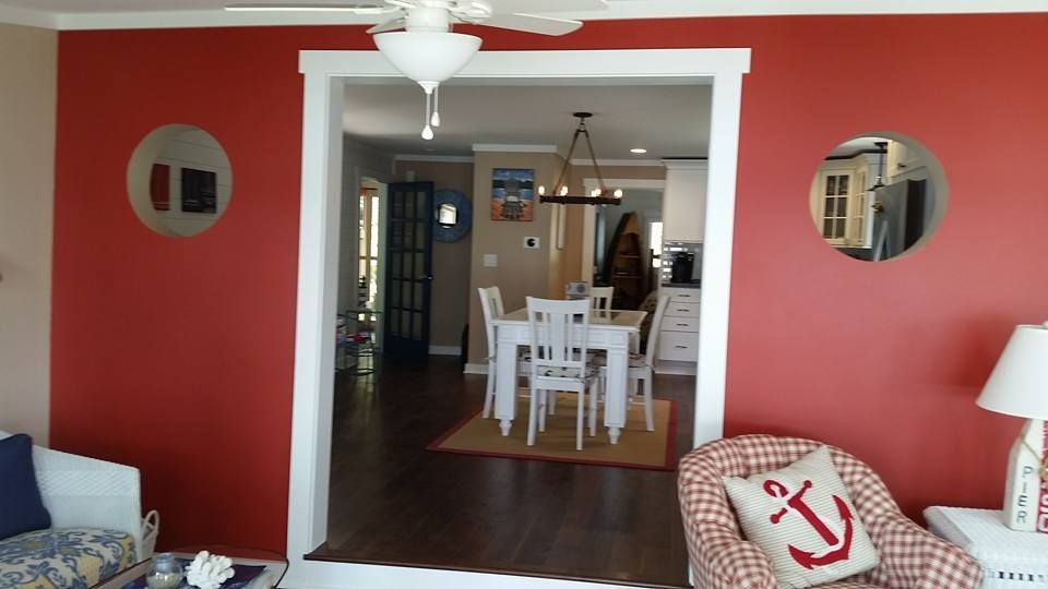 Red and tan room with doorway, white trim, dining area visible, round wall decor.