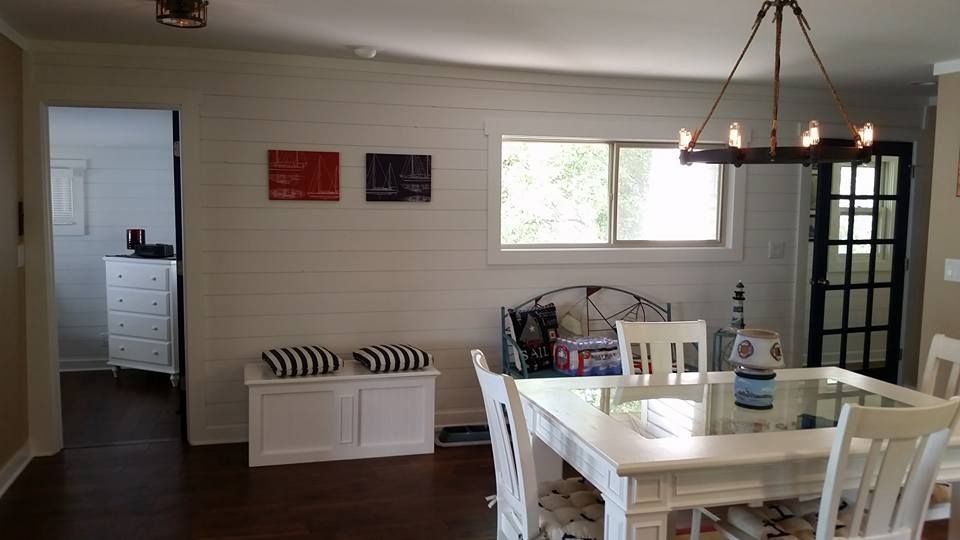 Dining room with white furniture, wood flooring, and light-colored walls. A doorway leads to another room.