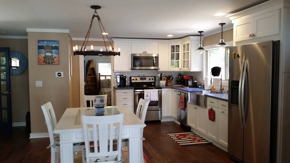 White kitchen with stainless steel appliances, white cabinets, and a farmhouse-style white dining table.