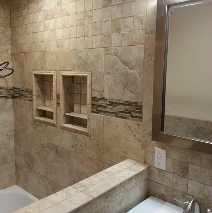 Bathroom with beige tiled walls, recessed shelves, and a mirror.
