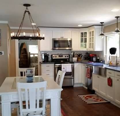 White kitchen with stainless steel appliances, white cabinets, and wooden floors.