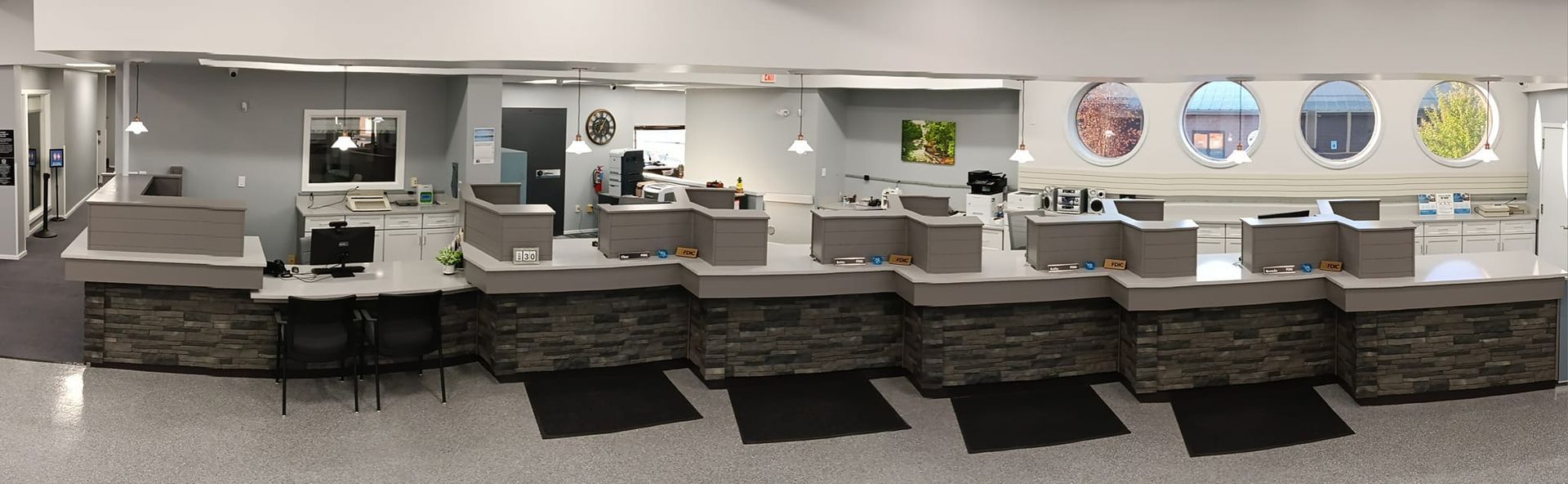 Interior view of a modern office reception area with multiple workstations and circular decorative windows.